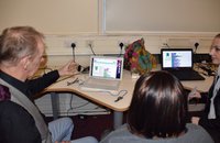 3 adults talking about data collected in front of laptop