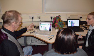 3 adults talking about data collected in front of laptop