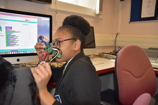 Girl showing a Codebug wearable controller in front of her face