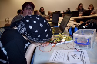 Girl looking at the LED ring that she's coded to visualise envrionmental data at the launch of Huddersfield Girl Geeks
